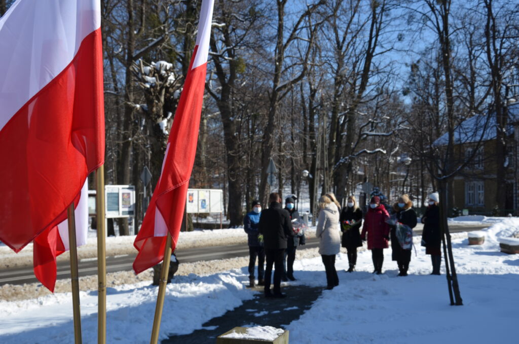 Zdjęcie przedstawia Pomnik Ofiar Faszyzmu, który usytuowany jest w centrum Jaworza. Dookoła powiewają białoczerwone flagi.